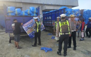 Foto : Personel Satlantas Polres Pamekasan memasang spanduk imbauan kepada sopir truk angkutan garam di area Gudang Garam, Desa Majungan, Kecamatan Pademawu, Kabupaten Pamekasan, Kamis (27/8/2026). Imbauan terkait penutupan muatan dengan terpal untuk mengantisipasi jalan licin akibat tetesan air garam.
