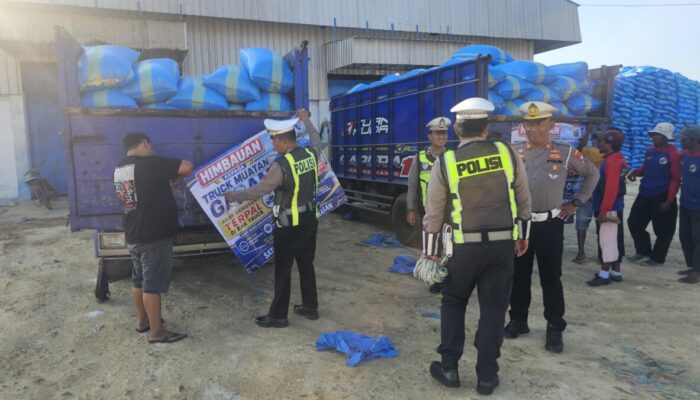 Foto : Personel Satlantas Polres Pamekasan memasang spanduk imbauan kepada sopir truk angkutan garam di area Gudang Garam, Desa Majungan, Kecamatan Pademawu, Kabupaten Pamekasan, Kamis (27/8/2026). Imbauan terkait penutupan muatan dengan terpal untuk mengantisipasi jalan licin akibat tetesan air garam.